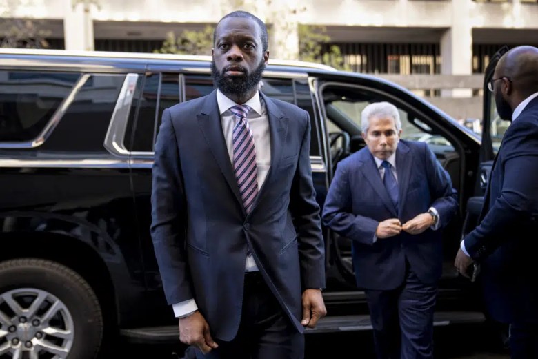 Prakazrel “Pras” Michel, center, a member of the 1990s hip-hop group the Fugees, accompanied by defense lawyer David Kenner, right, arrives at federal court for his trial in an alleged campaign finance conspiracy, Thursday, March 30, 2023, in Washington. (AP Photo/Andrew Harnik)