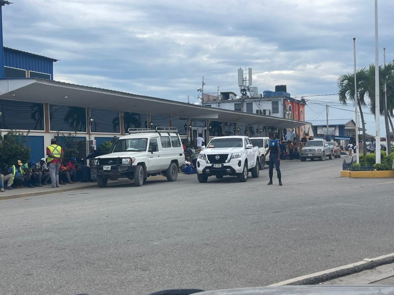An officer from the tourist protection unit of the Haitian National Police (Politour) does a routine check of cars entering the departure area of Cap-Haïtien’s Hugo Chavez International Airport on Monday, October 27, 2025. He is known in the town as ‘Le plus haut,’ French for ‘The tallest man,’ because of his height and especially slim appearance. Photo by Fritznel D. Octave/The Haitian Times
