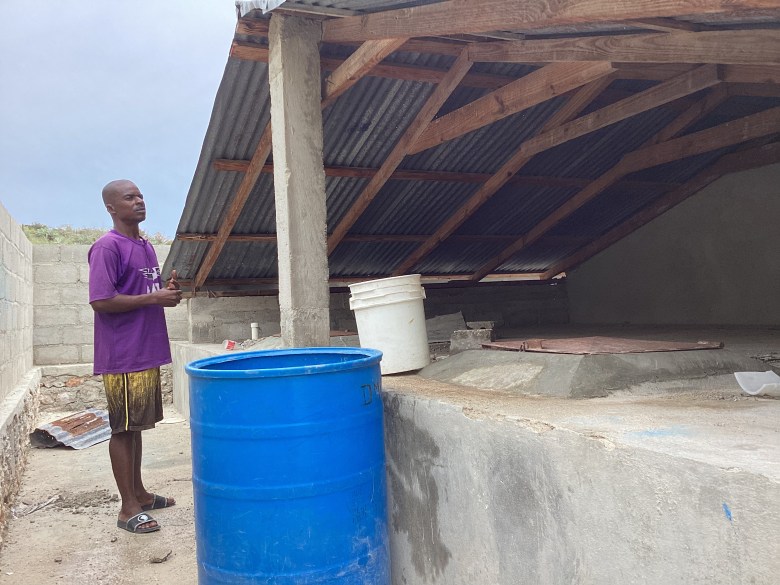 Sobnès Jean shows the rainwater cistern in Petit Anse, Baie-de-Henne, on Sunday, November 2, 2025, while highlighting the community’s other urgent needs, including healthcare and infrastructure for critical socioeconomic activities. Photo by Fritznel D. Octave/The Haitian Times. 


