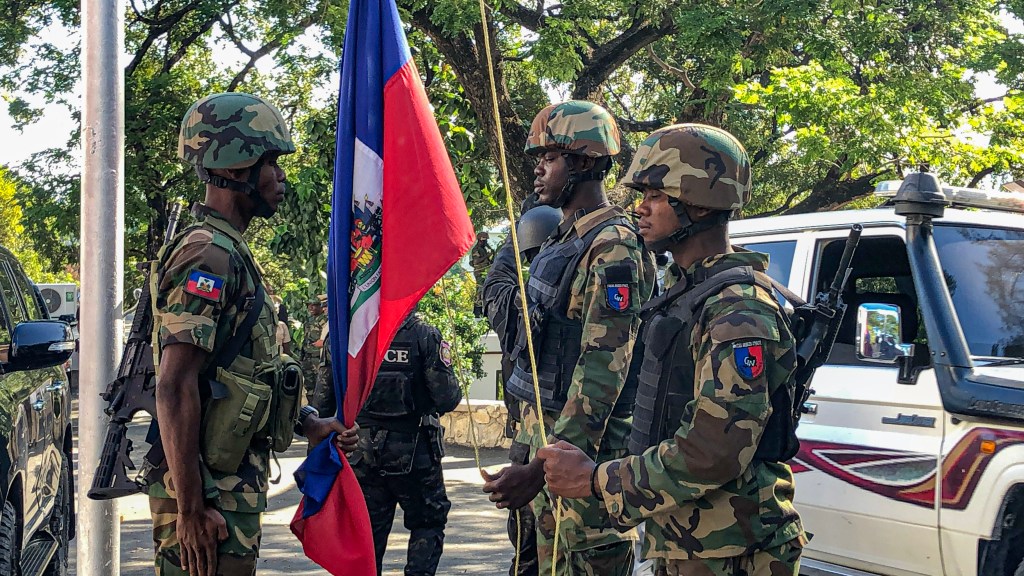 Three Haitian Armed Forces (FADH) officers stand proudly during the flag-raising ceremony, celebrating Haiti's 221st Independence Day anniversary. Photo by Arnold Junior Pierre for Haitian Times.
